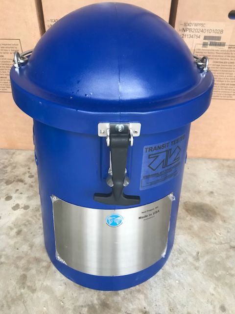 A blue cylindrical MVE SC 4/2V vapor shipper by Chart/MVE with domed lid, metal latch, silver panel, and blue sticker sits on a concrete floor before cardboard boxes. It holds up to 280 straws and comes with a three-year vacuum warranty.