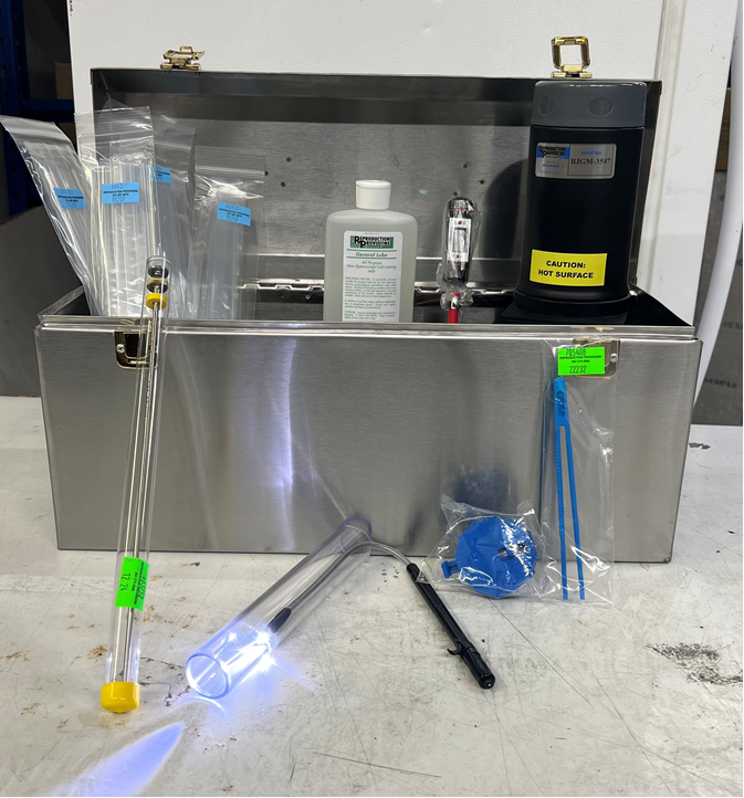 The RR Goat AI kit includes a metal box containing lab essentials such as a digital thaw unit, plastic bags, bottle, thermometer, glass tubes, flashlight, zip ties, and a blue tool—all neatly arranged in front of the open box.