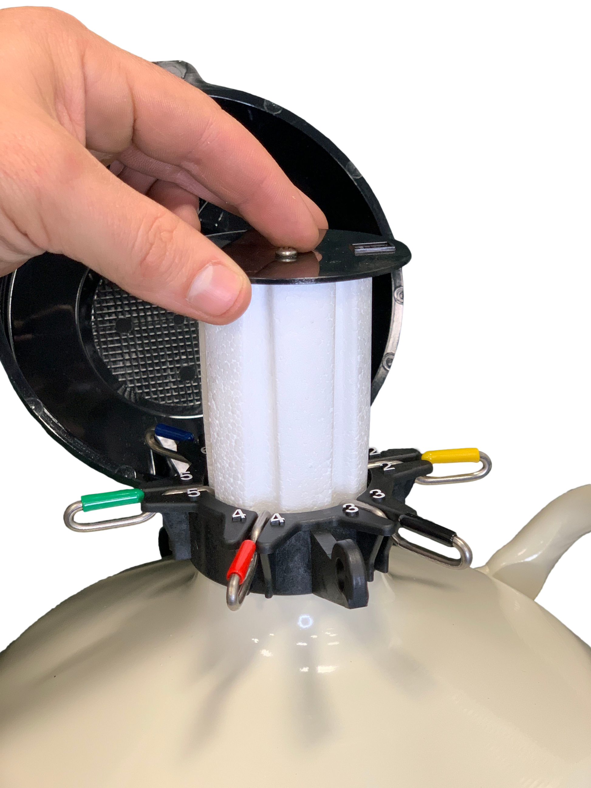 A hand installs or removes a white filter with black top from a Chart/MVE XC 20 Signature liquid nitrogen tank (holds 660 straws for 20 weeks) featuring four color-coded clips and a round open lid for safe semen storage.