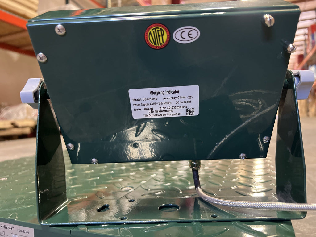 A close-up of the CRYO-ALERT Floor Scale from Semen Tanks - Select Genetics, a green 110-lb weight indicator with stack light, shows its model and certification labels mounted on a metal platform in an industrial setting.