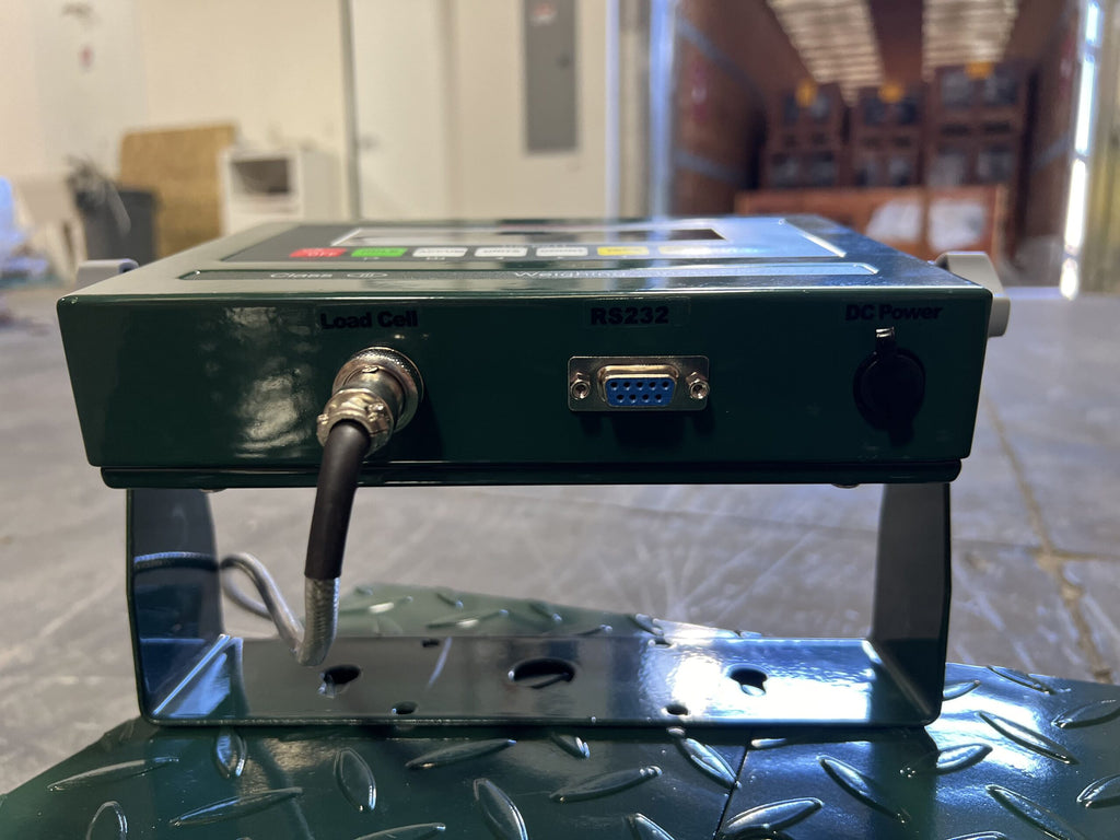Close-up of the Semen Tanks - Select Genetics CRYO-ALERT Floor Scale (110 lbs), a green weight indicator with labeled Load Cell, RS232, and DC Power ports, mounted on metal for industrial semen tank weighing.