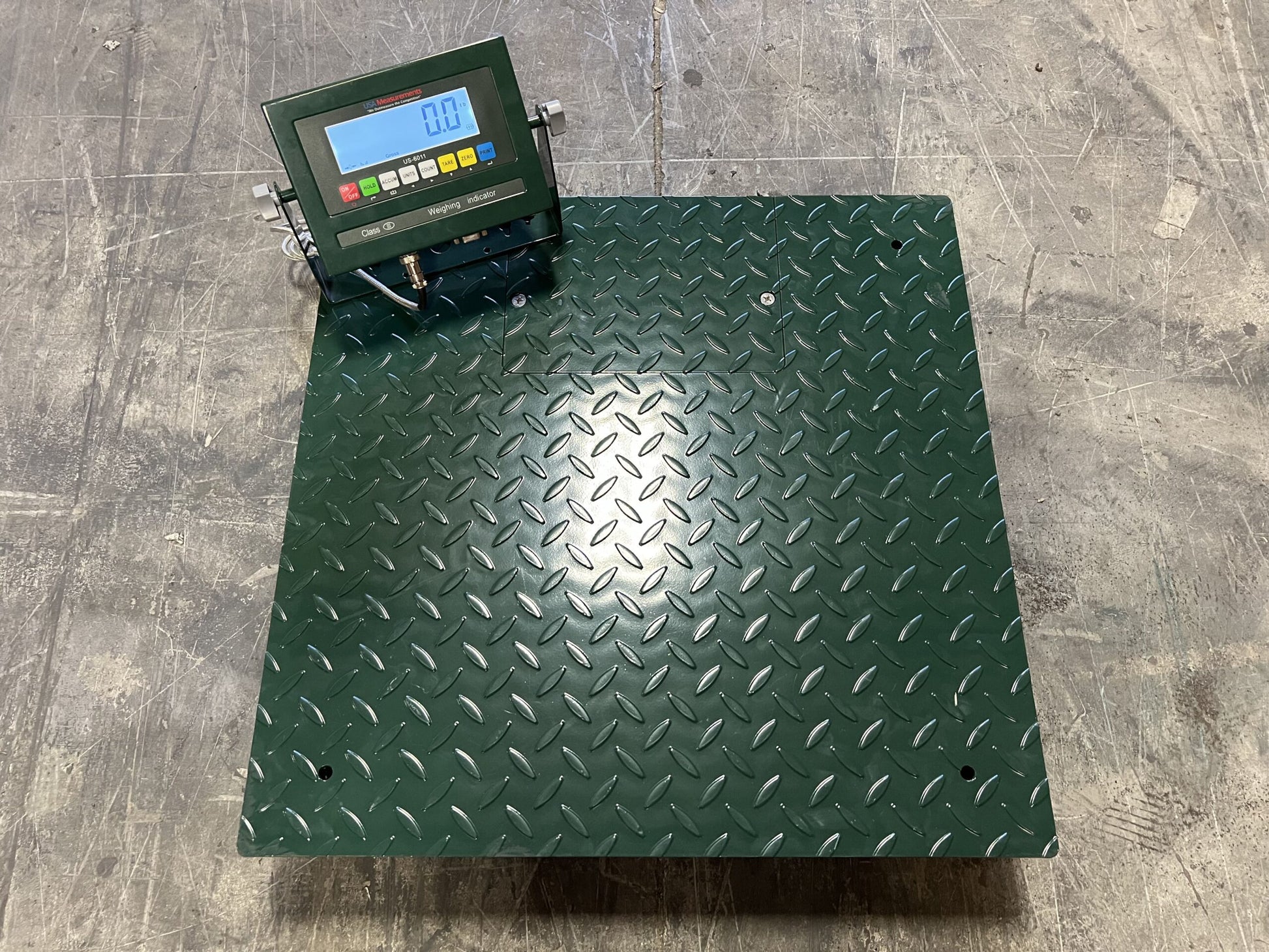 The Semen Tanks - Select Genetics CRYO-ALERT Floor Scale features a diamond plate surface and attached weight indicator, displaying 0.0 on a concrete floor—perfect for accurate tank monitoring in industrial settings.