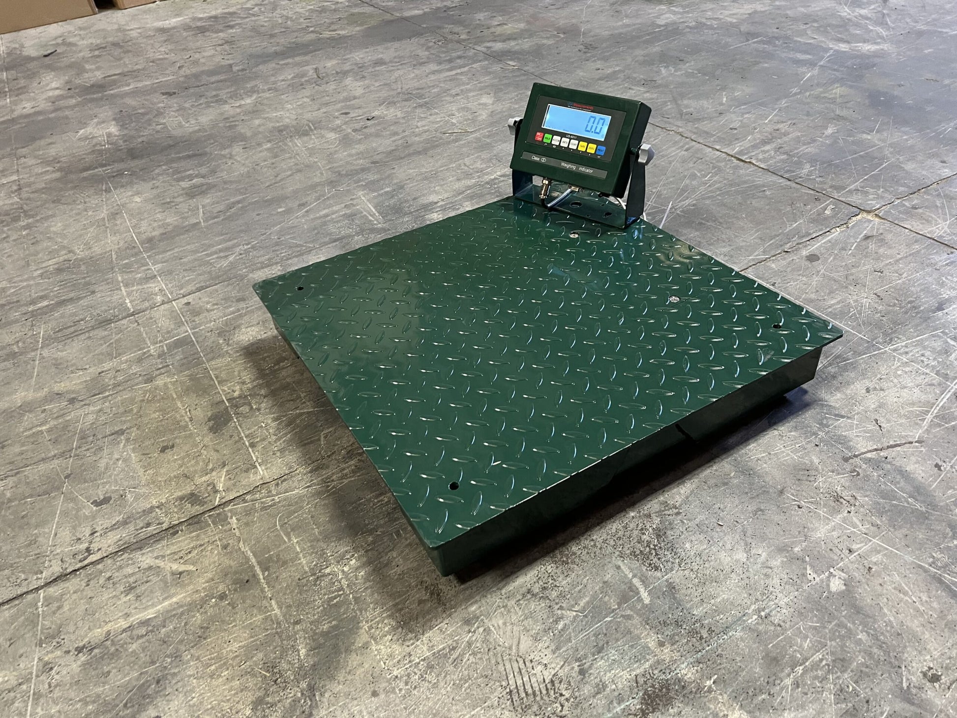 The CRYO-ALERT Floor Scale by Semen Tanks - Select Genetics features a digital weight indicator, stack light, 110 lb capacity, diamond plate surface, and angled control panel with buttons and screen—ideal for industrial weighing on concrete floors.