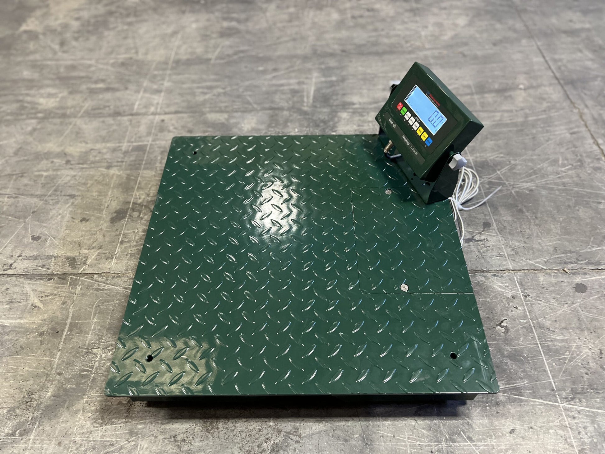 The CRYO-ALERT Floor Scale by Semen Tanks - Select Genetics, with a weight indicator and stack light, weighs up to 110 lbs and is ideal for semen or embryo tank monitoring. White cables connect its display as it sits on a gray concrete floor.