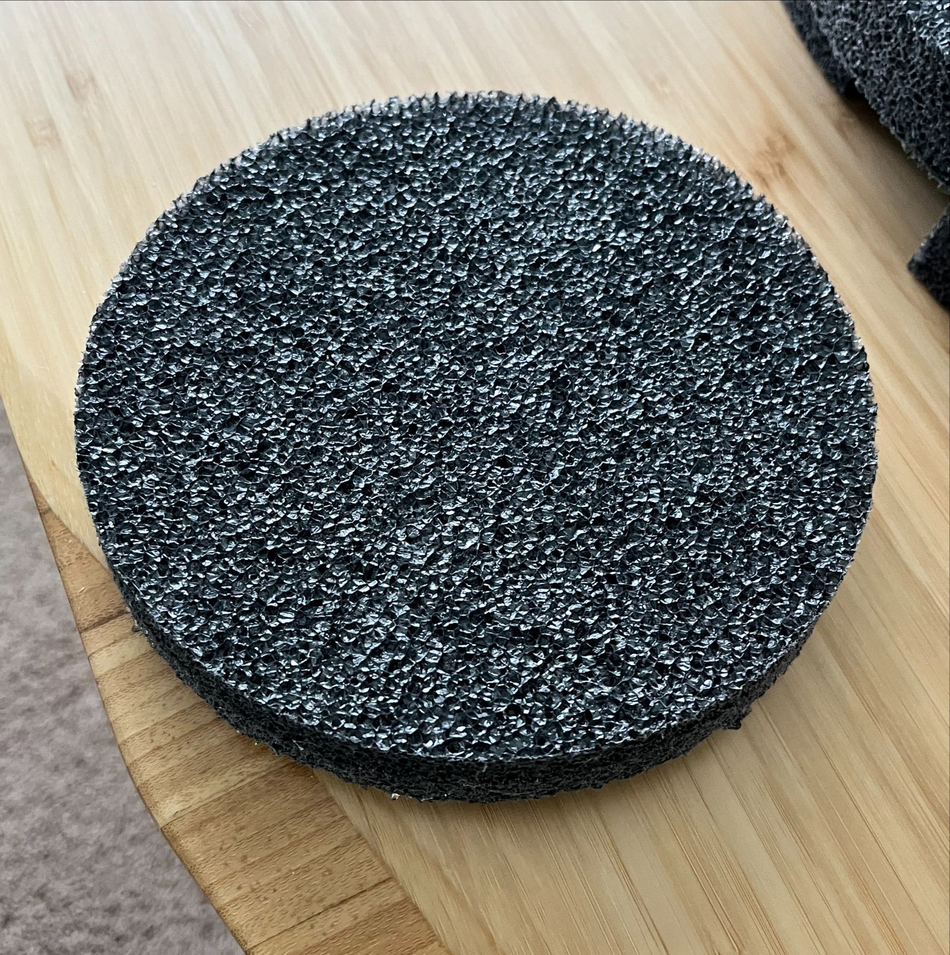 A round, black, porous foam pad from Chart/MVE sits on a light wooden surface—ideal as a TOTAL KIT Foam Replacement Piece (sides, top, bottom) for 4/2 & 4/3 V mushroom MVE Protective Shipping Containers.