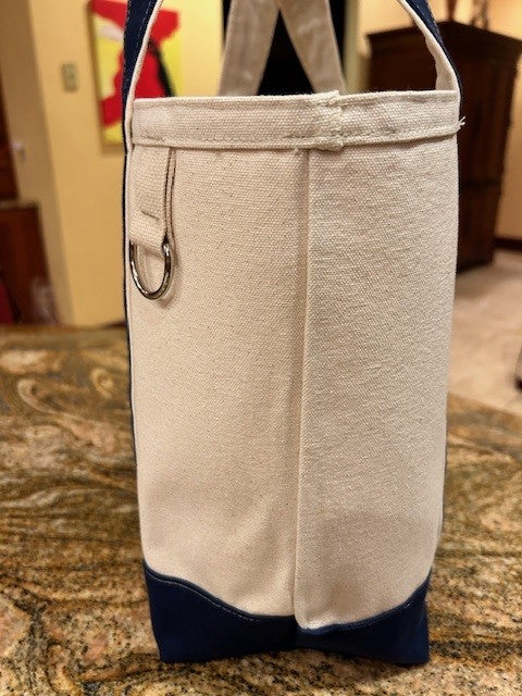 A close-up side view of the Semen Tanks - Select Genetics Totes for Everyday Use, featuring denim accents and a metal ring on the side, shown on a brown patterned surface—ideal for pairing with rolling luggage.