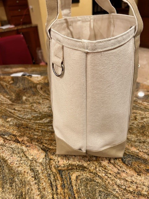 The Semen Tanks - Select Genetics Totes for Everyday Use in beige, with 18 or 24 inch straps, rests on a granite counter. Roomy and sturdy, its ideal daily. A red chair and wooden cabinets are in the background.