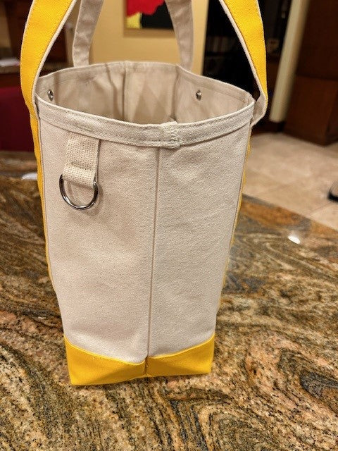 A close-up of the Semen Tanks - Select Genetics Totes for Everyday Use with yellow accents and 24-inch straps, made in USA white duck canvas, featuring a metal ring on the side, shown indoors on a granite countertop.