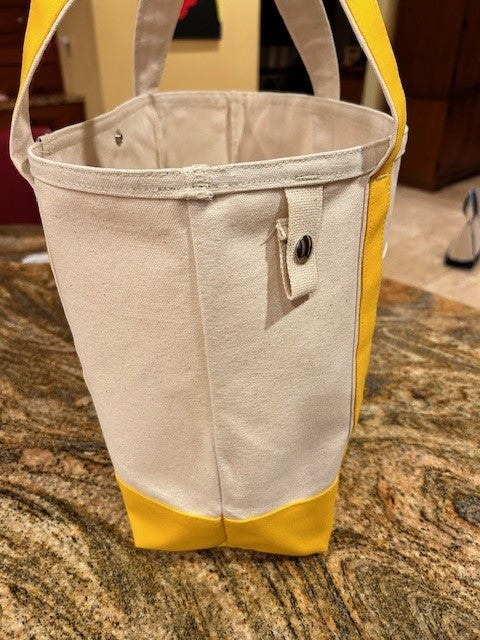 The Semen Tanks - Select Genetics Totes for Everyday Use features yellow accents and 24-inch straps. Made in the USA, it stands upright on a brown marble countertop and has a snap button tab on the side.
